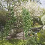 7' Metal Garden Arbor, Garden Arch with Gate, Fleur De Lis Motif, Latching Doors, Planter Shelves for Climbing Vines, Ceremony, Weddings, Party, Garden, Backyard, Lawn, Brown - Image 2